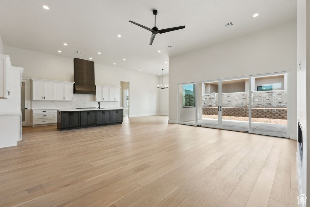 Unfurnished living room featuring light wood-style floors, a ceiling fan, recessed lighting, a towering ceiling, and visible vents