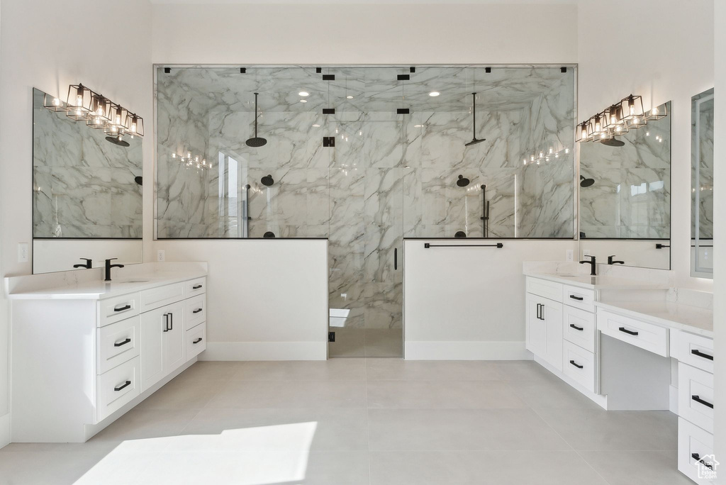 Full bath featuring a sink, a marble finish shower, and two vanities