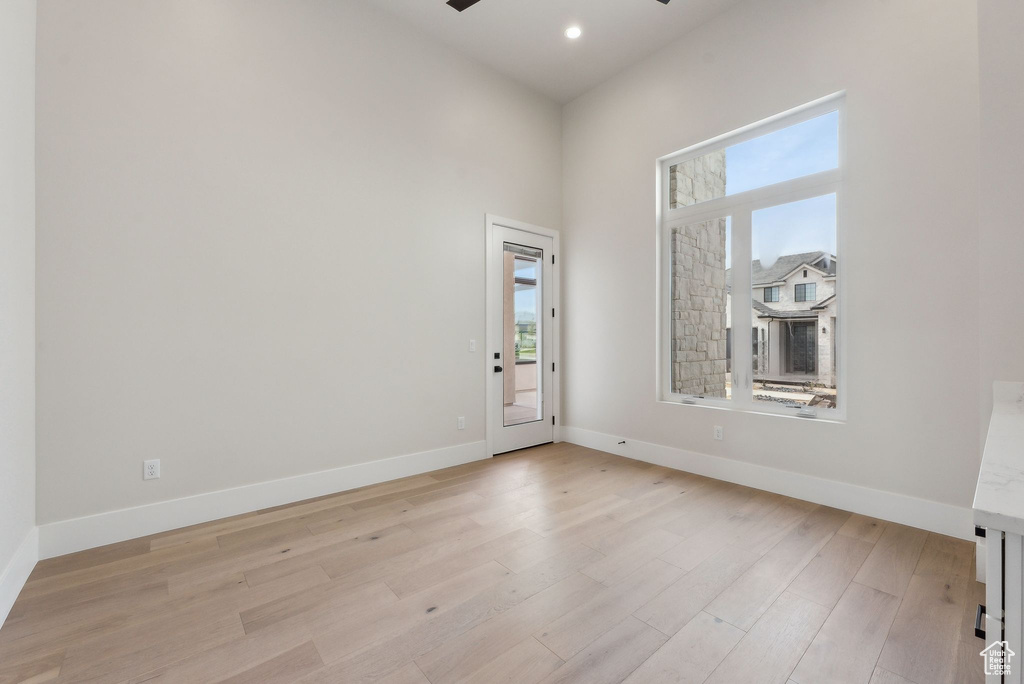 Unfurnished room featuring light wood-style floors, baseboards, ceiling fan, and a wealth of natural light