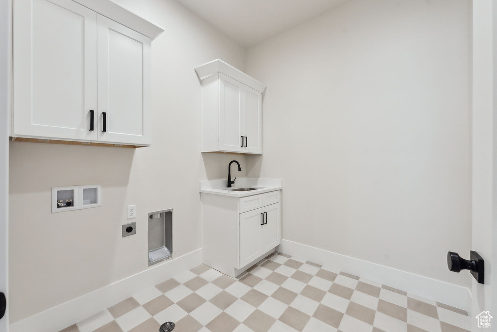 Laundry room with hookup for a washing machine, light floors, electric dryer hookup, a sink, and cabinet space