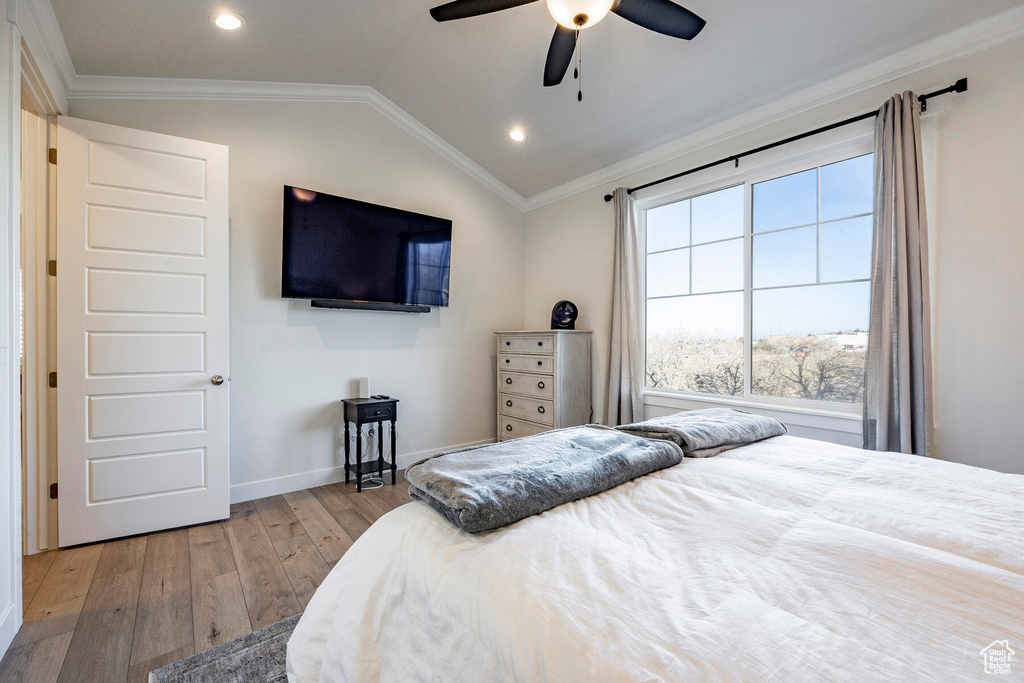 Bedroom with ornamental molding, light wood-type flooring, lofted ceiling, and ceiling fan