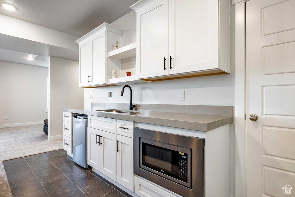 Kitchen featuring sink, stainless steel appliances, white cabinets, and dark tile floors