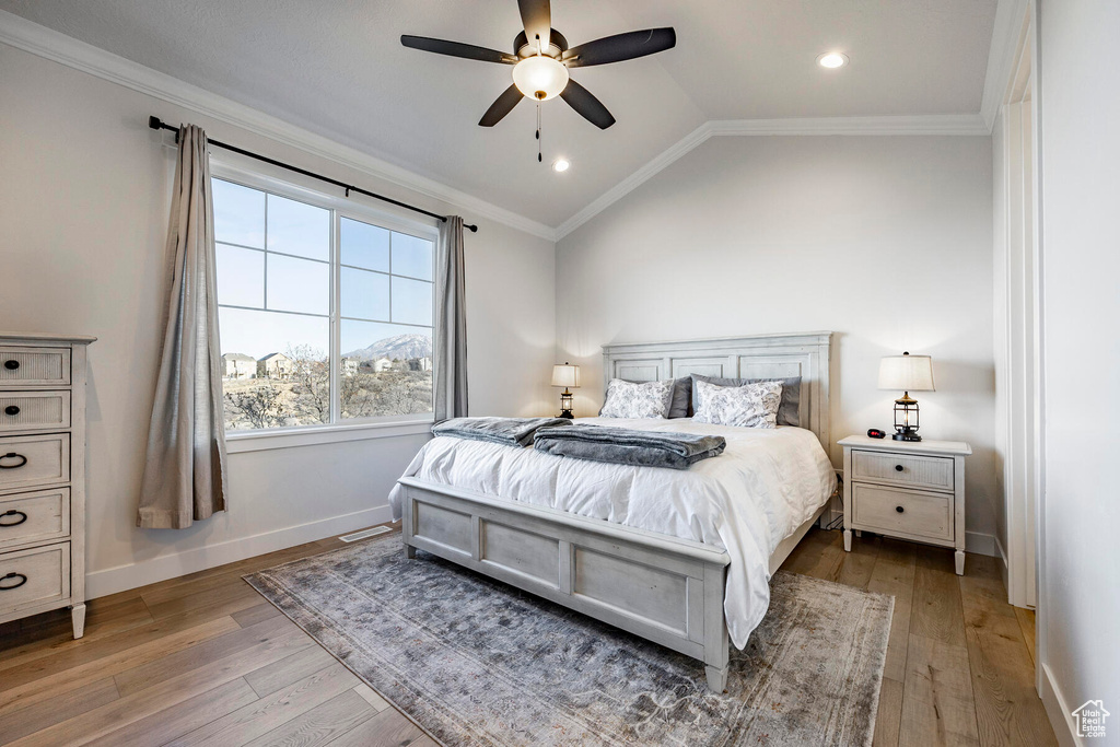 Bedroom with ornamental molding, vaulted ceiling, light wood-type flooring, and ceiling fan