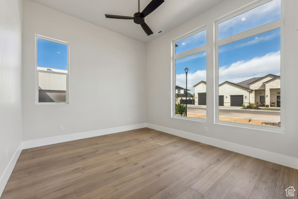 Spare room with baseboards, ceiling fan, hardwood / wood-style flooring, and visible vents