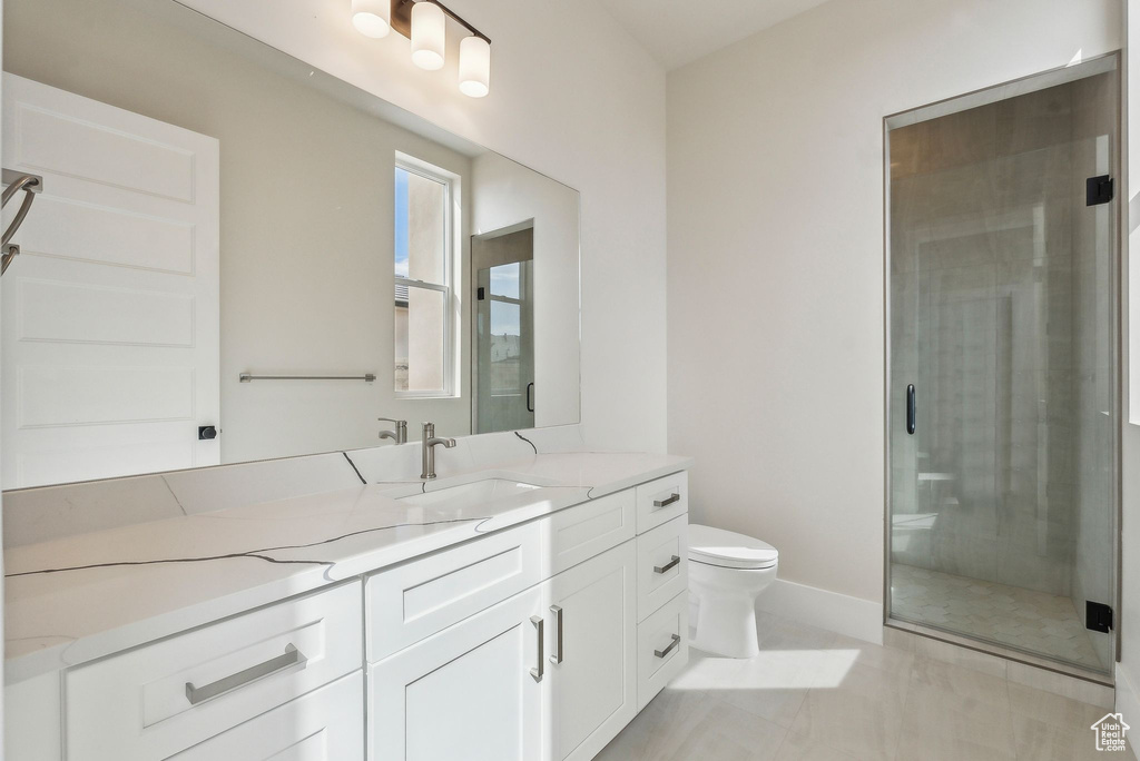 Bathroom featuring vanity, baseboards, a stall shower, and toilet