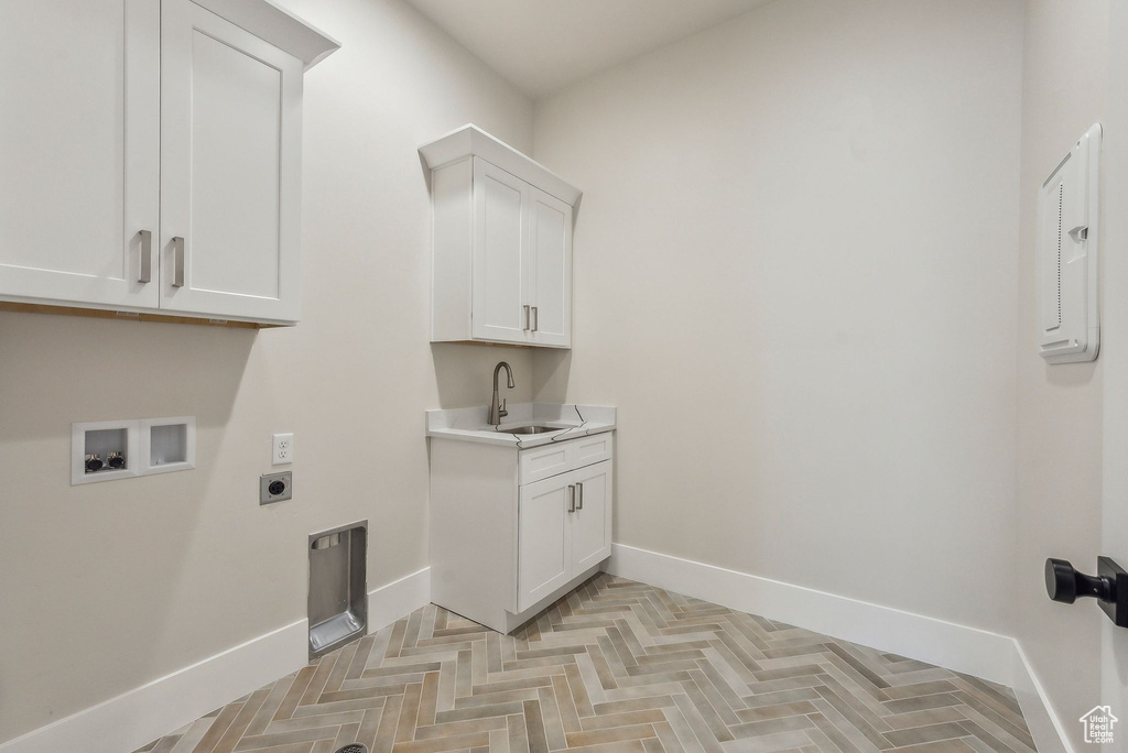 Washroom featuring electric dryer hookup, cabinet space, a sink, baseboards, and hookup for a washing machine