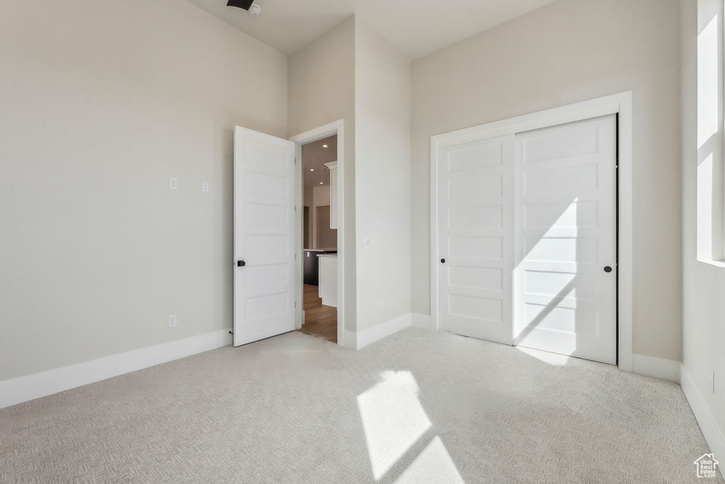 Unfurnished bedroom with light colored carpet and baseboards