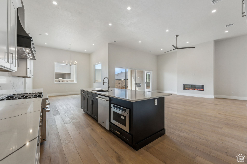 Kitchen featuring recessed lighting, light countertops, a sink, ceiling fan with notable chandelier, and stainless steel appliances