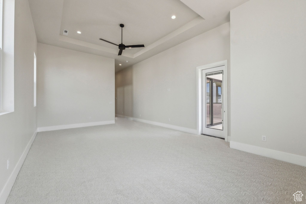 Carpeted spare room with baseboards, ceiling fan, a tray ceiling, and recessed lighting
