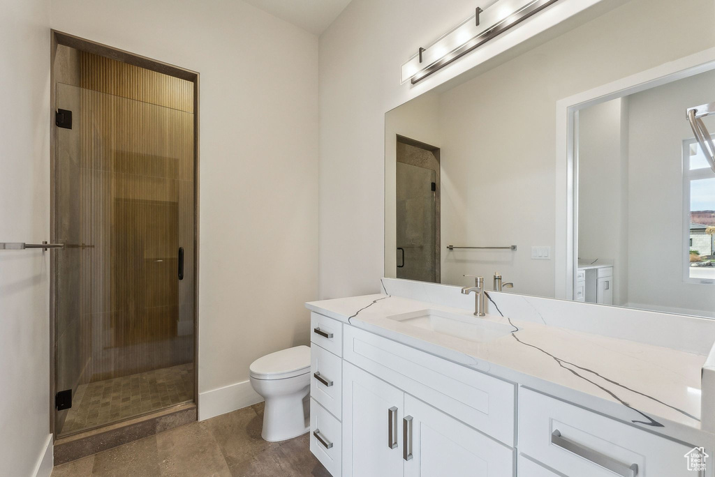 Bathroom with vanity, baseboards, a stall shower, and toilet