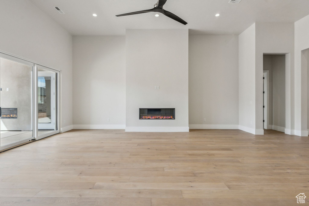 Unfurnished living room featuring recessed lighting, a ceiling fan, a glass covered fireplace, and light wood finished floors