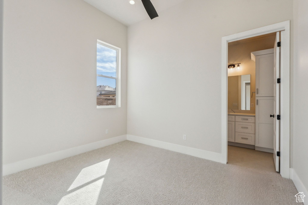 Unfurnished bedroom featuring a ceiling fan, baseboards, light carpet, and ensuite bath