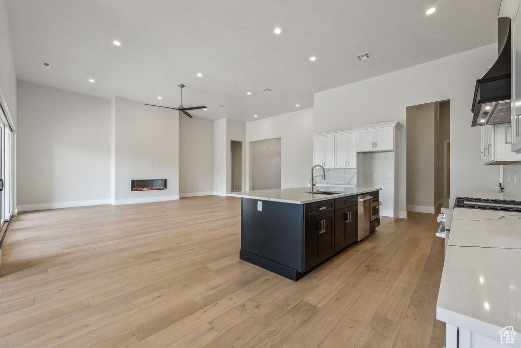 Kitchen featuring white cabinets, ceiling fan, a sink, light wood-style floors, and light countertops