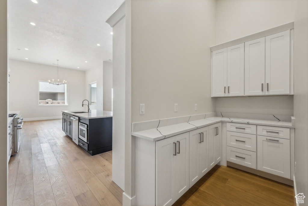 Kitchen with white cabinets, recessed lighting, and light wood-style flooring