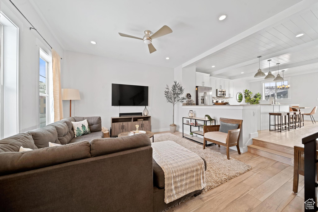 Living room featuring beam ceiling, ceiling fan, light hardwood / wood-style floors, and plenty of natural light
