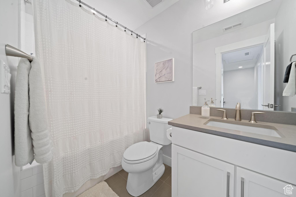Bathroom with large vanity, toilet, and tile flooring