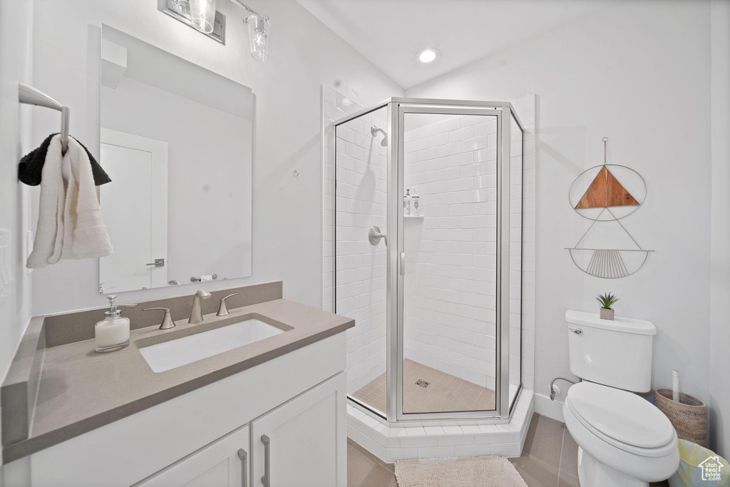 Bathroom featuring toilet, vanity with extensive cabinet space, and a shower with door