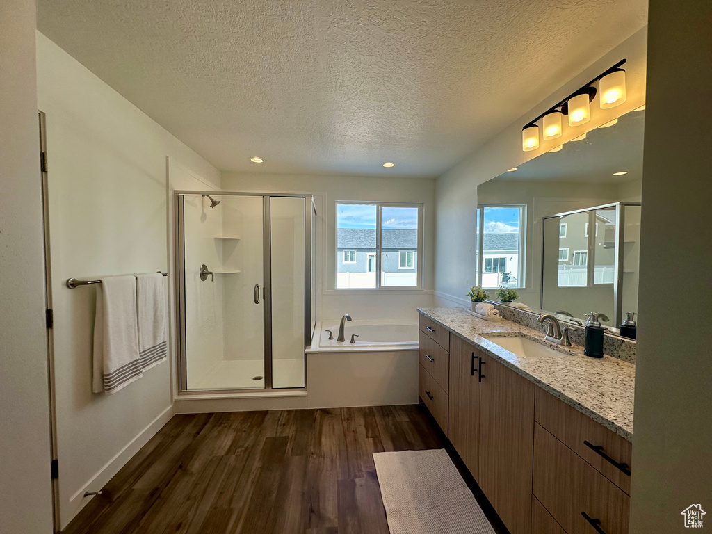 Bathroom featuring hardwood / wood-style flooring, vanity, a textured ceiling, and shower with separate bathtub