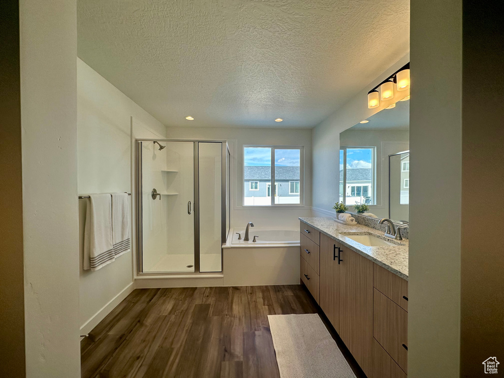 Bathroom with vanity, a textured ceiling, separate shower and tub, and hardwood / wood-style floors