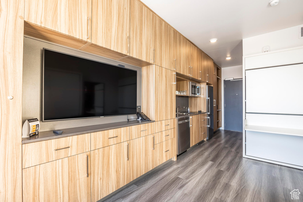 Kitchen with appliances with stainless steel finishes, light brown cabinets, and dark wood-type flooring