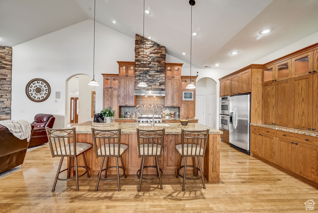 Kitchen featuring pendant lighting, a kitchen bar, stainless steel appliances, and light wood-type flooring