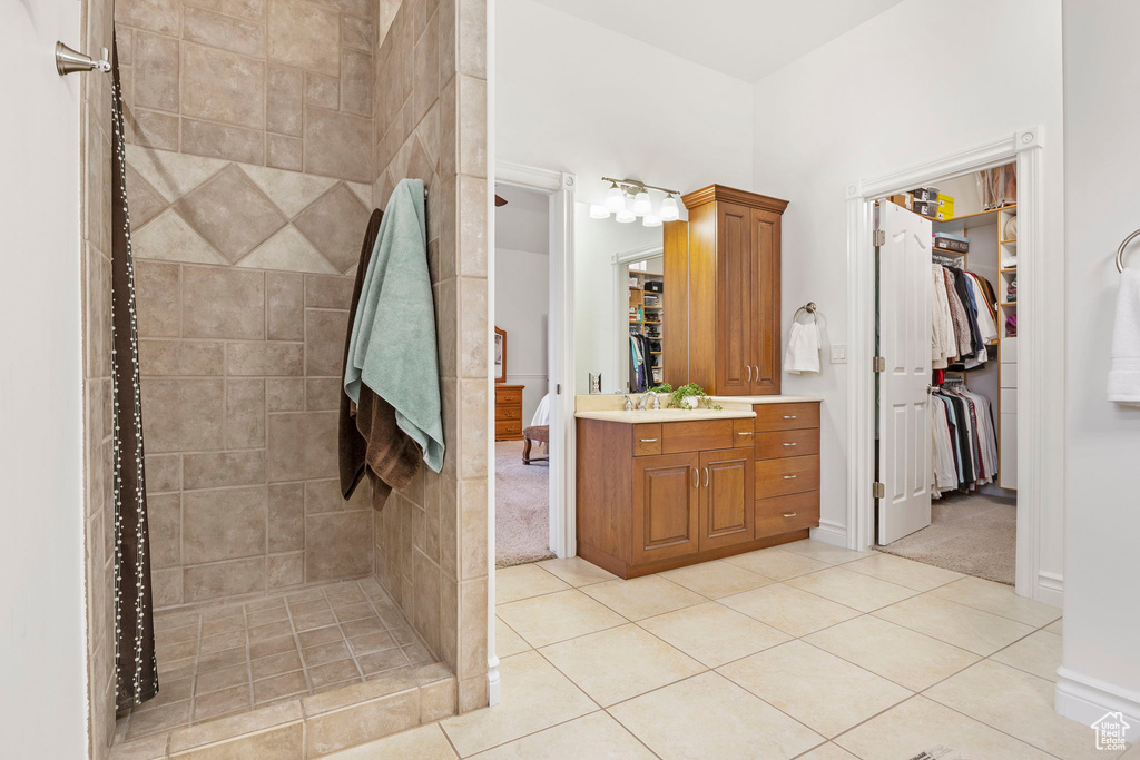 Bathroom with tiled shower, vanity, and tile flooring