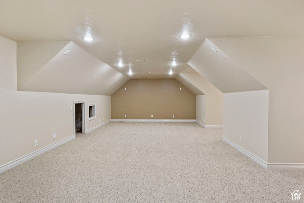 Bonus room featuring vaulted ceiling and light carpet