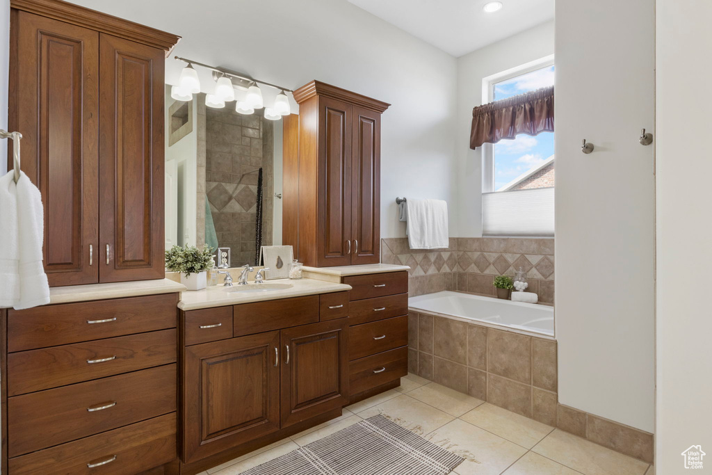 Bathroom featuring tile flooring, a relaxing tiled bath, and large vanity