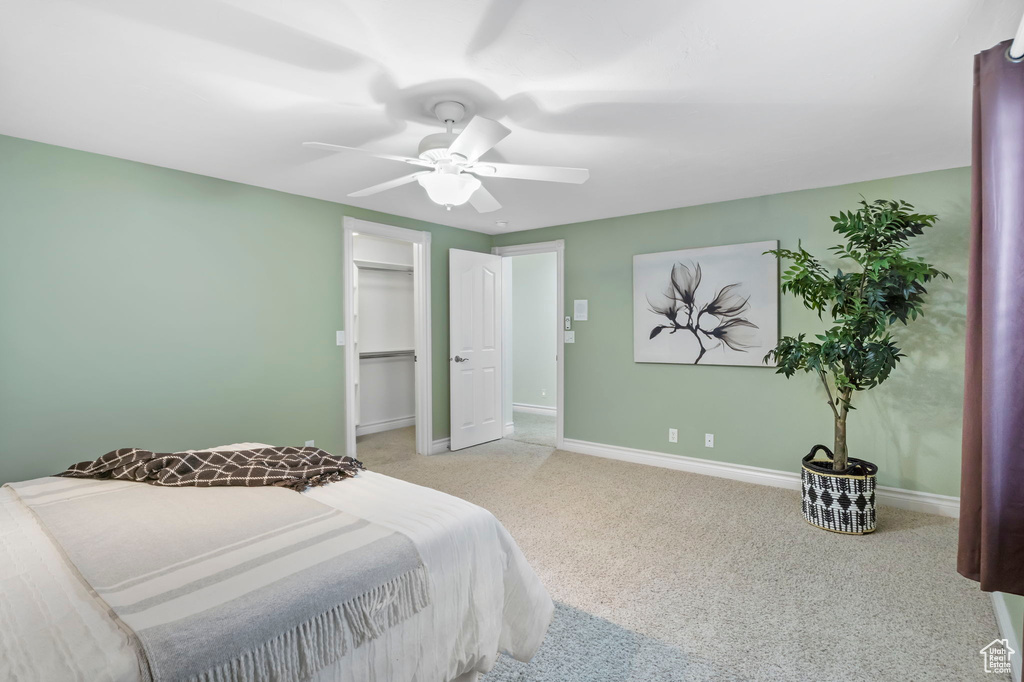 Bedroom featuring light colored carpet, a closet, a spacious closet, and ceiling fan