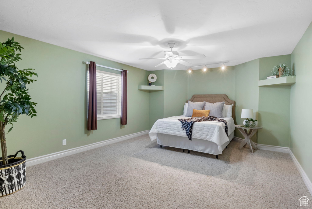 Bedroom with light colored carpet, track lighting, and ceiling fan