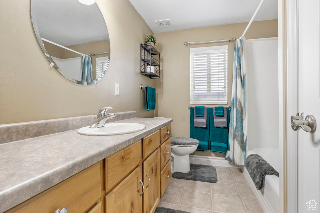 Full bathroom featuring large vanity, toilet, tile flooring, and shower / bathtub combination with curtain