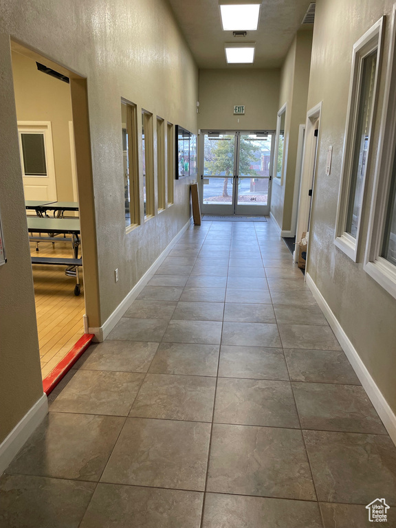 Hall with a towering ceiling, tile flooring, and french doors