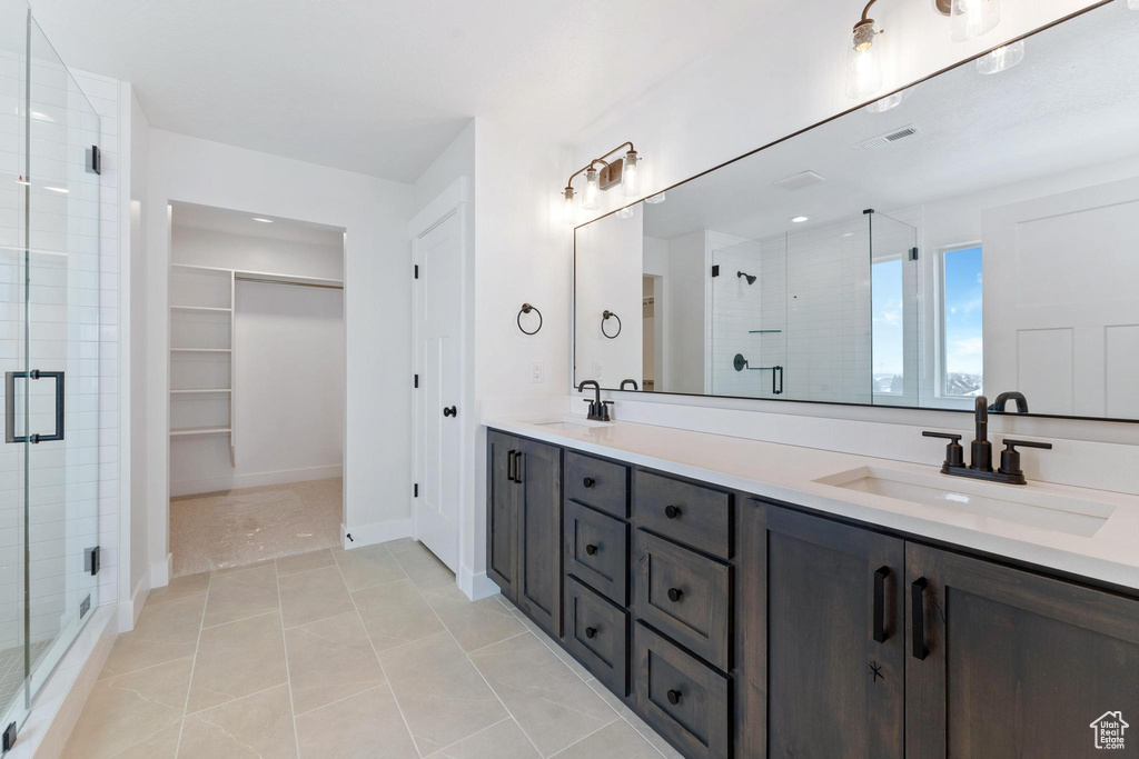 Bathroom with walk in shower, tile flooring, double sink, and vanity with extensive cabinet space