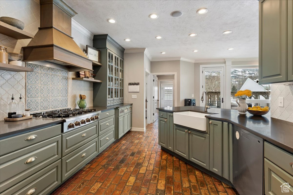 Kitchen featuring custom range hood, stainless steel appliances, ornamental molding, backsplash, and sink