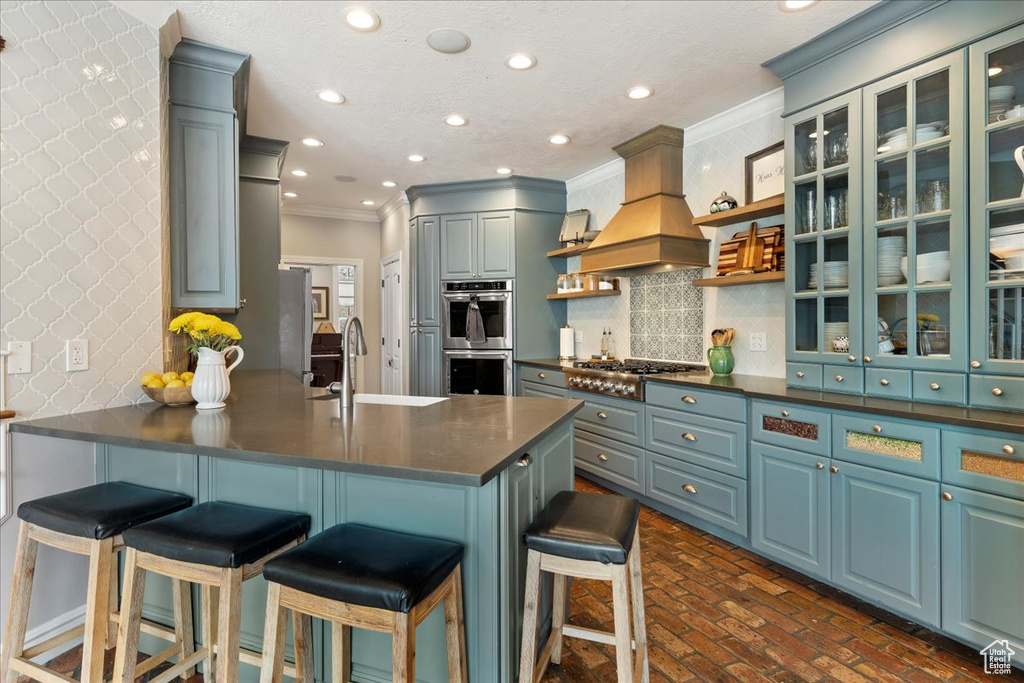 Kitchen with crown molding, premium range hood, kitchen peninsula, backsplash, and stainless steel appliances