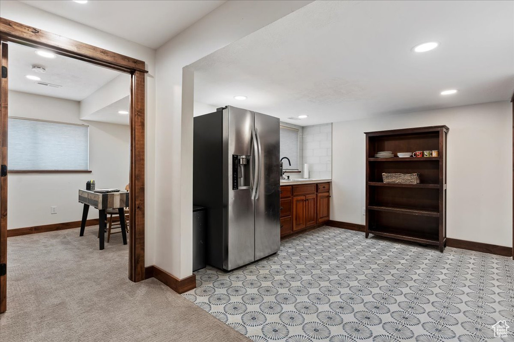 Kitchen featuring sink, stainless steel refrigerator with ice dispenser, and light tile floors