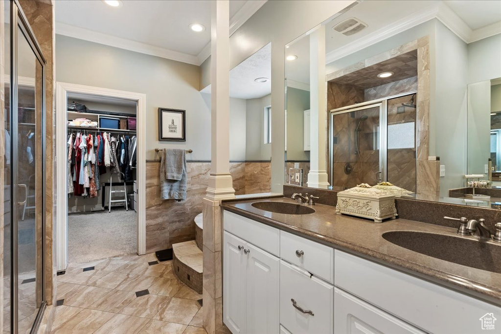 Bathroom with crown molding, oversized vanity, walk in shower, decorative columns, and tile flooring
