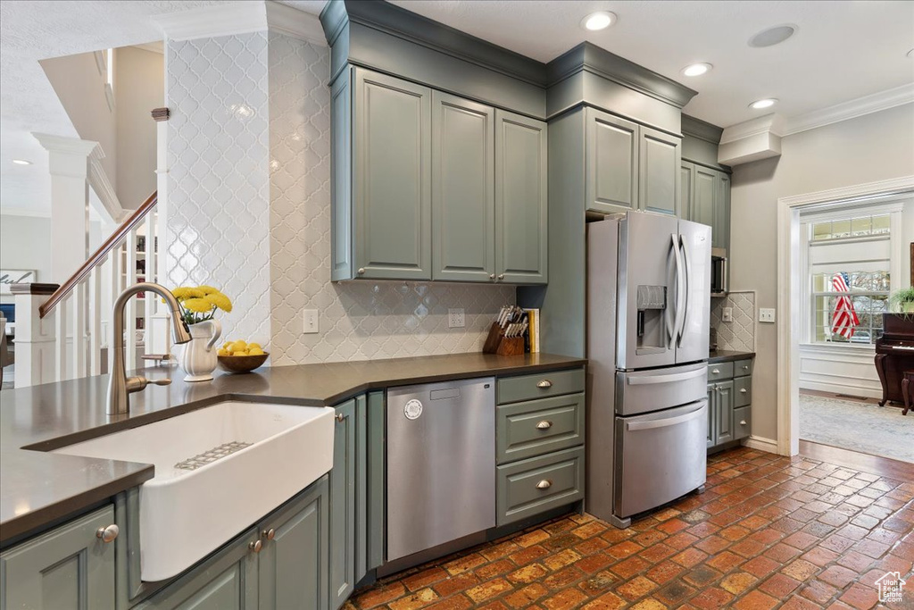 Kitchen with ornamental molding, appliances with stainless steel finishes, sink, and backsplash