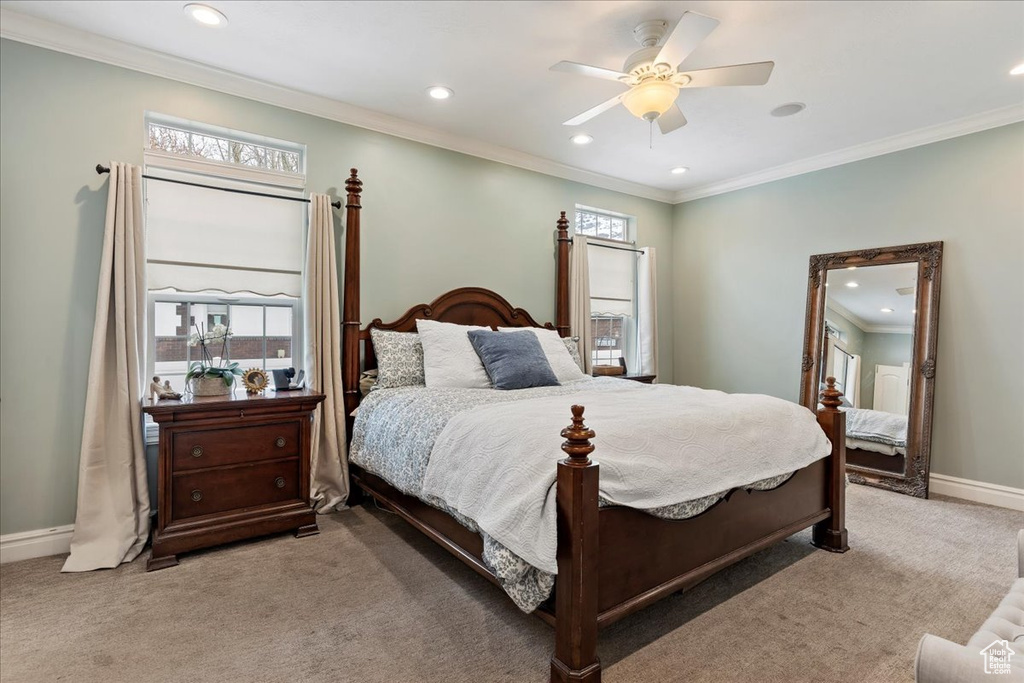 Bedroom with ornamental molding, light colored carpet, and ceiling fan