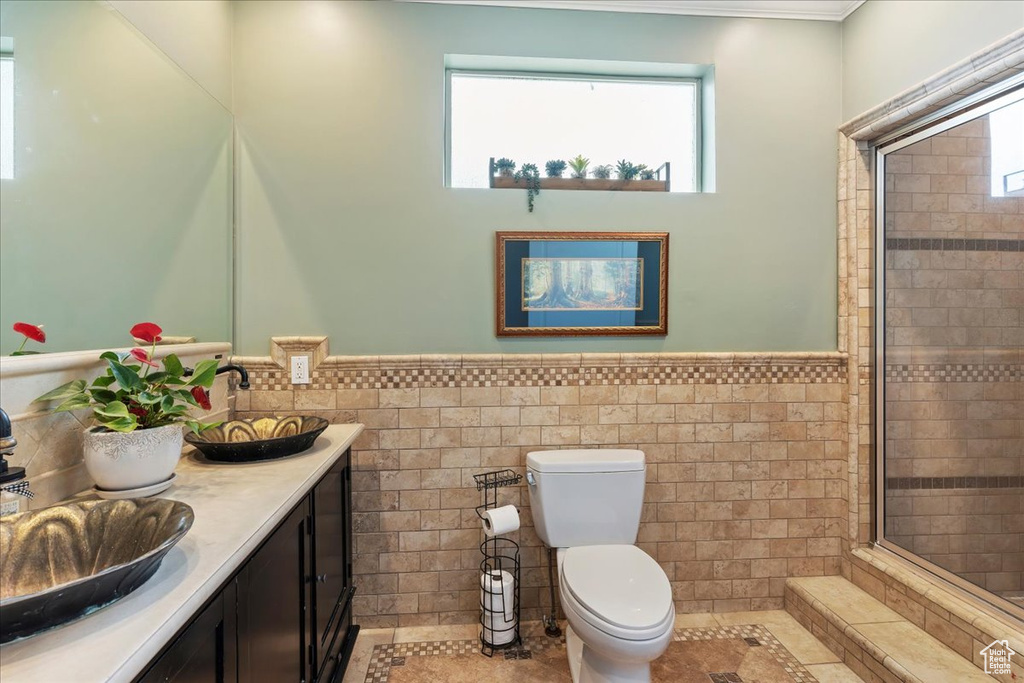 Bathroom with toilet, large vanity, tile floors, tile walls, and tiled shower