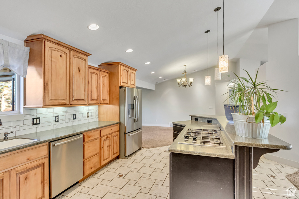 Kitchen featuring tasteful backsplash, light stone countertops, a notable chandelier, decorative light fixtures, and stainless steel appliances