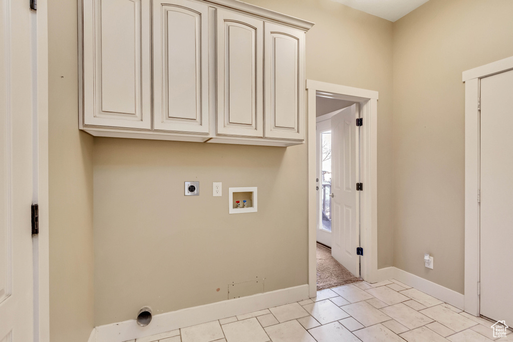 Washroom with light tile flooring, cabinets, hookup for a washing machine, and electric dryer hookup
