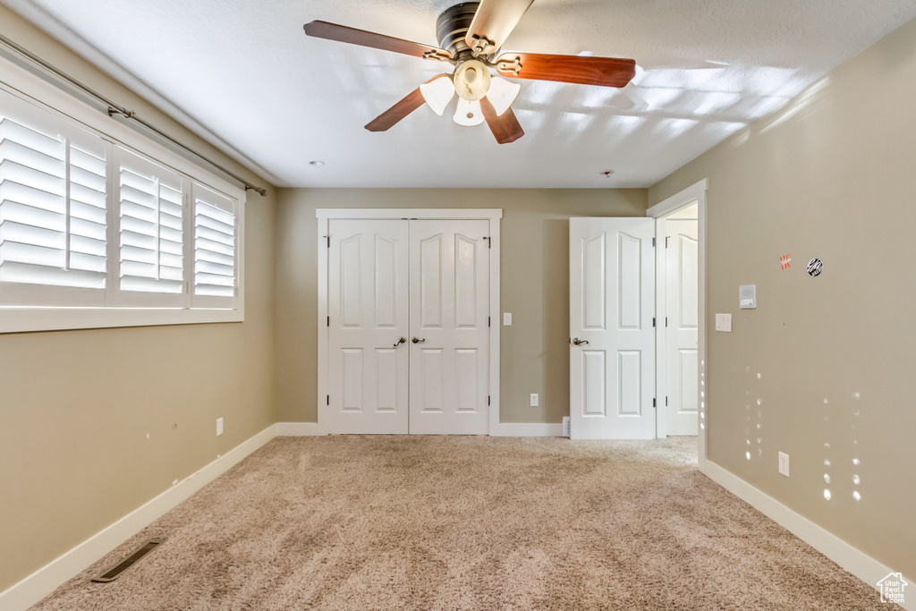 Unfurnished bedroom with a closet, carpet floors, and ceiling fan