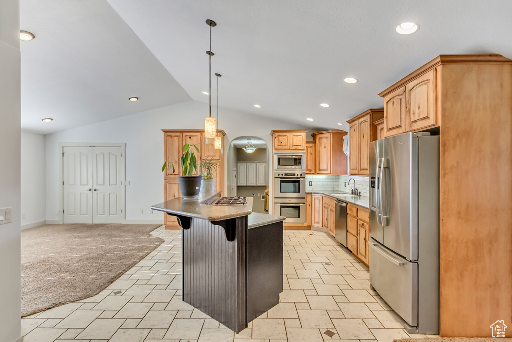 Kitchen with a kitchen island, light tile floors, tasteful backsplash, vaulted ceiling, and stainless steel appliances