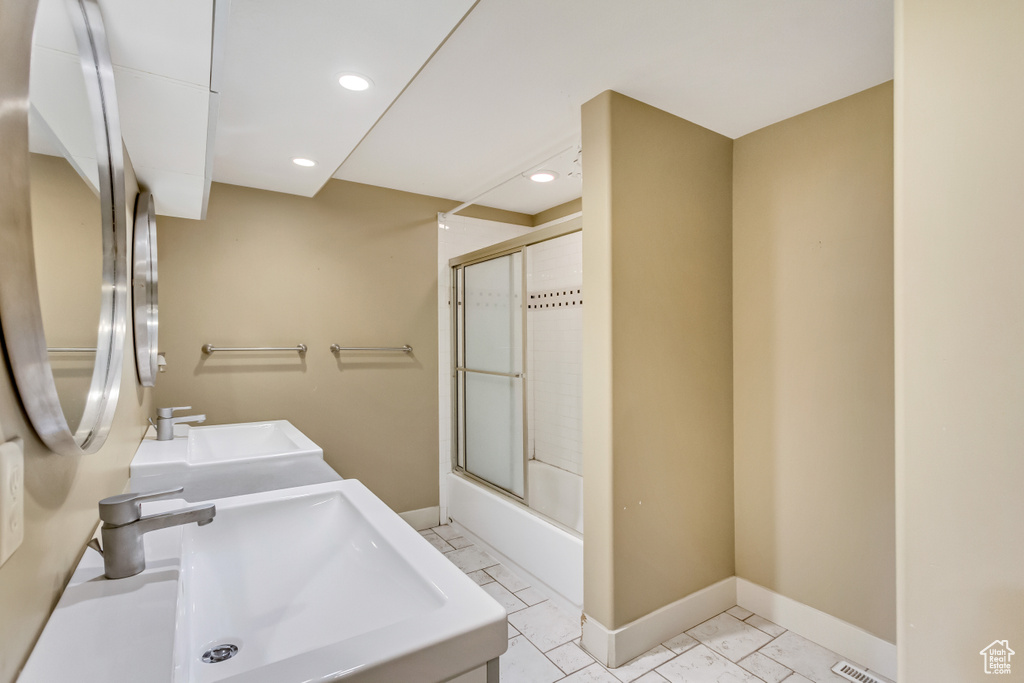 Bathroom with double vanity, tile flooring, and combined bath / shower with glass door