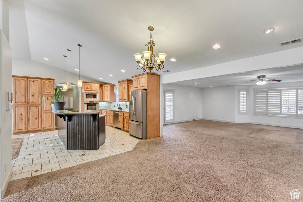 Kitchen with a center island, light carpet, stainless steel appliances, and a kitchen bar
