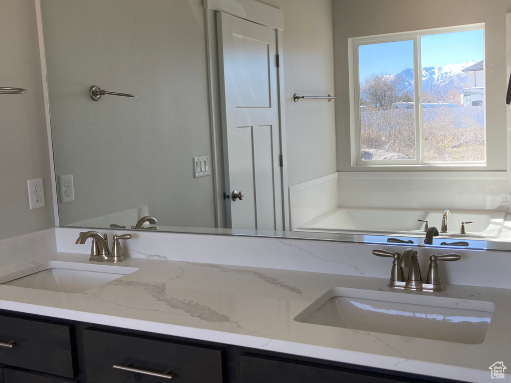 Bathroom with a healthy amount of sunlight, oversized vanity, and dual sinks