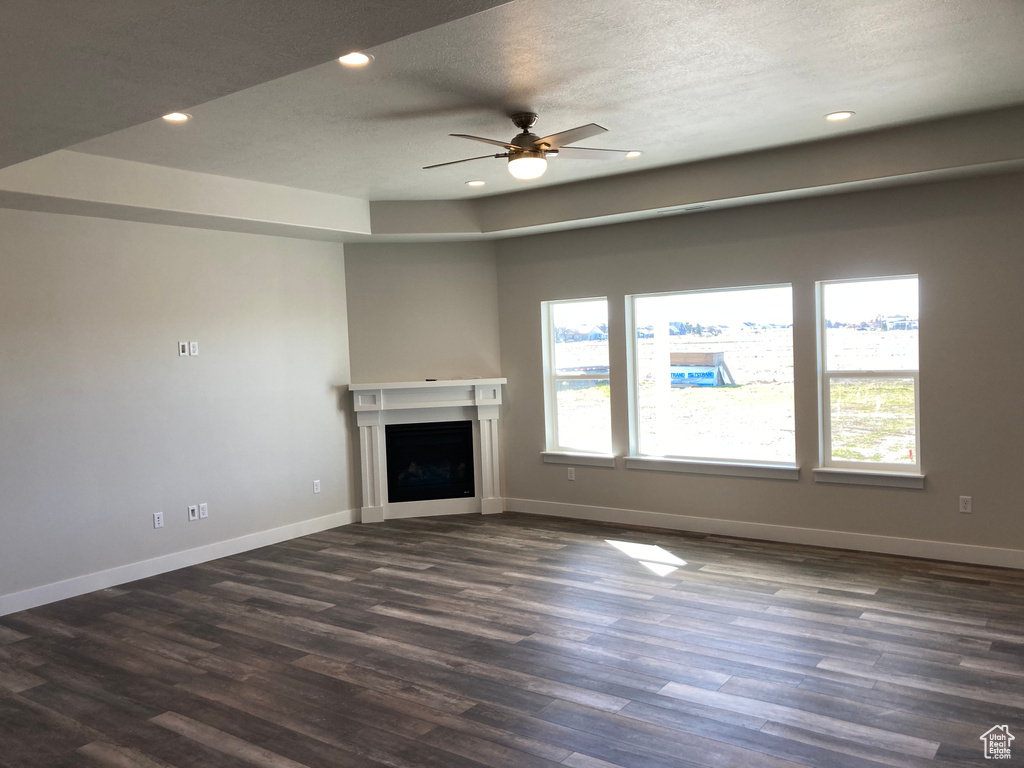 Unfurnished living room featuring dark hardwood / wood-style flooring, a textured ceiling, and ceiling fan