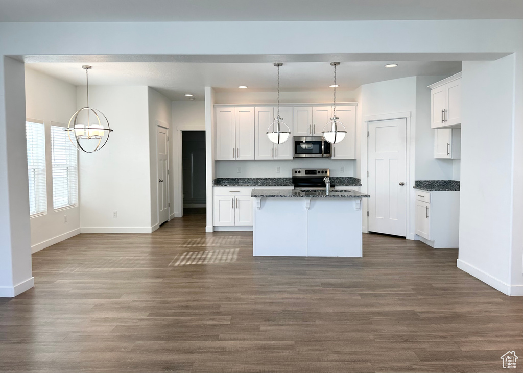 Kitchen featuring hanging light fixtures, white cabinets, appliances with stainless steel finishes, and dark wood-type flooring