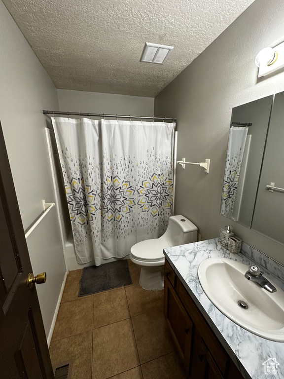 Full bathroom featuring shower / bath combination with curtain, toilet, vanity with extensive cabinet space, tile flooring, and a textured ceiling